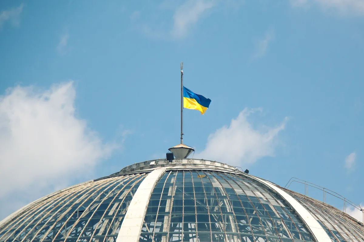 The glass dome of the Verkhovna Rada building in Kyiv, with the flag of Ukraine flying above it.