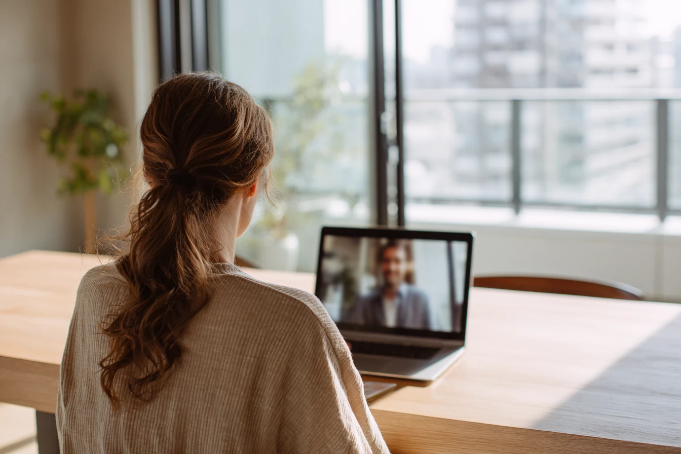 Seen from behind: a mentor at her table in a one-to-one video session.