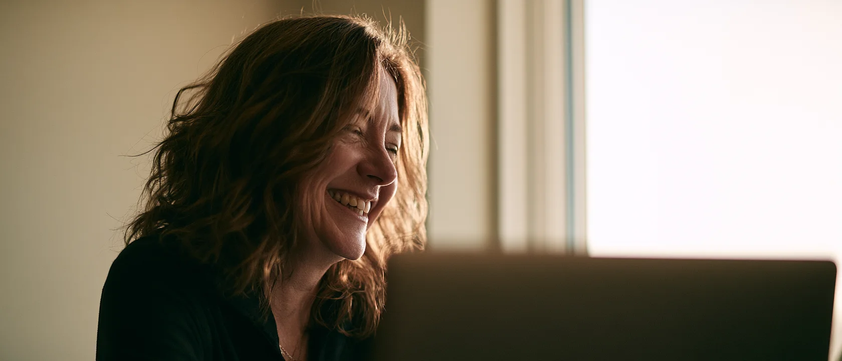 A volunteer laughing mid-conversation on a video call at her laptop.