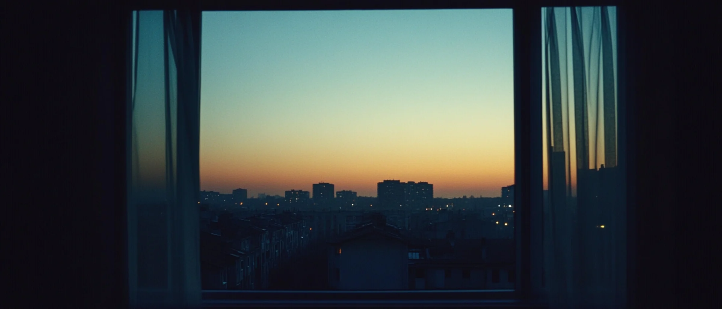 First light of dawn over a quiet city, seen from a window