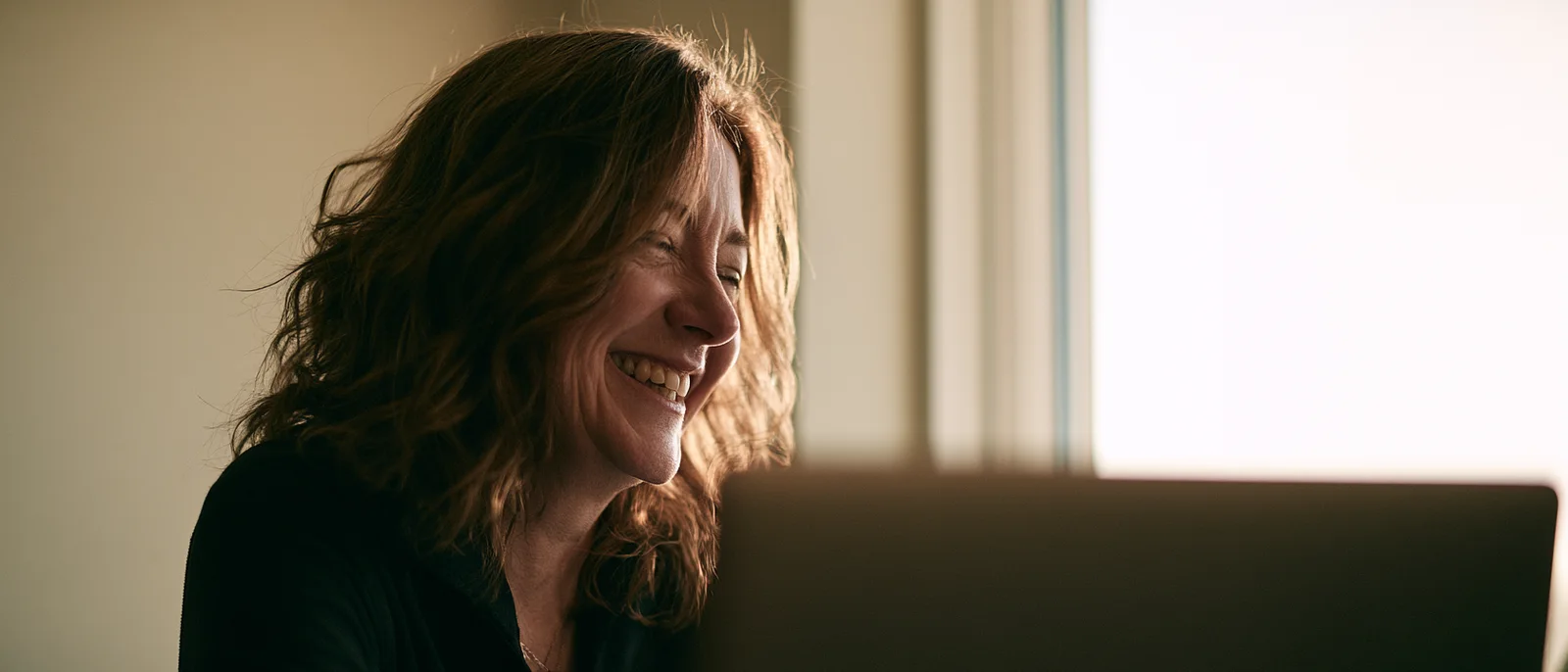 A woman laughing warmly during a video conversation